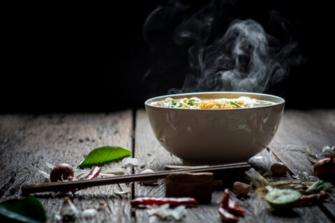 Noodles,With,Steam,And,Smoke,In,Bowl,On,Wooden,Background,