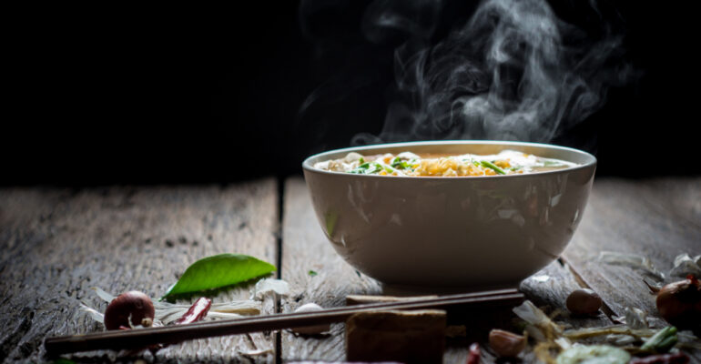 Noodles,With,Steam,And,Smoke,In,Bowl,On,Wooden,Background,
